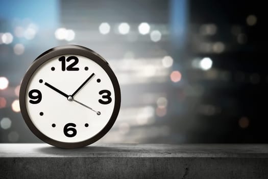 One black clock on the low wall with blurred city lights. Earth Hour Concept.