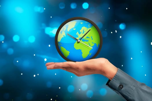 People hand showing earth globe clock against blue light background