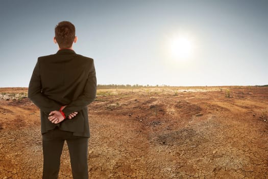 Back view of asian businessman on dry ground and sunset. Climate change concept