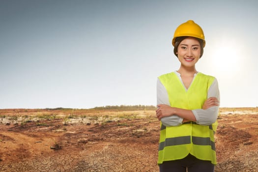 Young asian engineer woman with reflective vest on construction field background