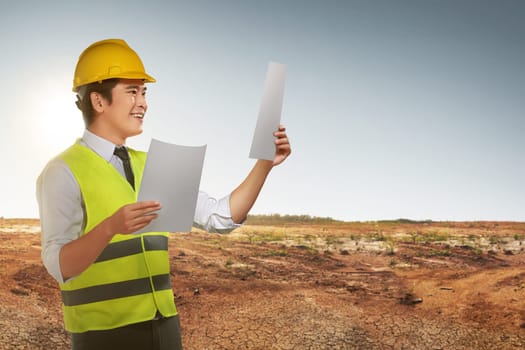 Portrait of asian worker man looking his blueprints at construction site
