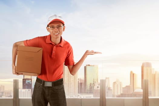Young asian male postal delivery courier over skyscraper background