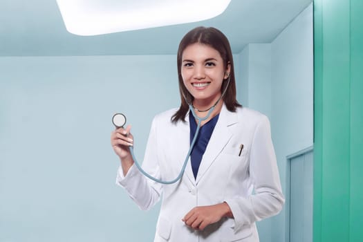 Attractive asian female doctor in white coat with stethoscope in medical office