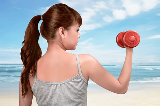 Attractive asian woman works out with dumbbells as a fitness on the beach