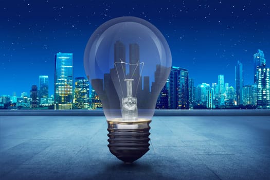 Light bulb on building balcony on city at night. Earth Hour Concept.