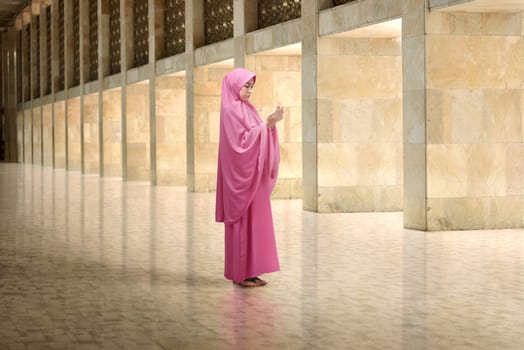 Young asian muslim woman with veil dress praying in the mosque