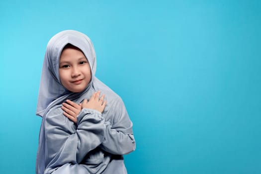 Small asian girl in hijab with smile face over blue background