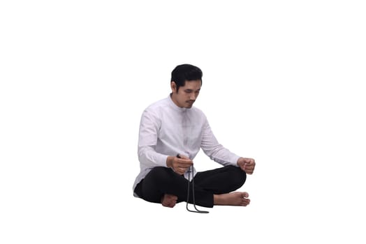 Young asian muslim man with prayer beads praying isolated over white background