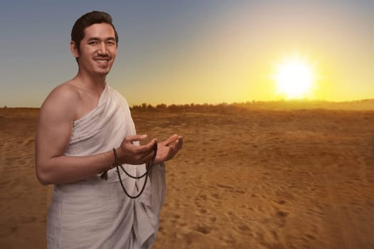 Handsome asian muslim man in ihram dress with prayer beads ready for hajj