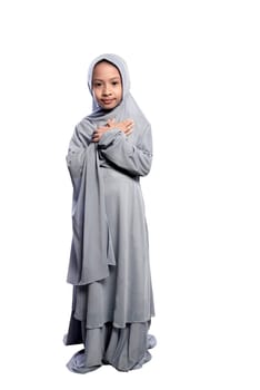 Portrait of asian muslim child wearing hijab standing isolated over white background