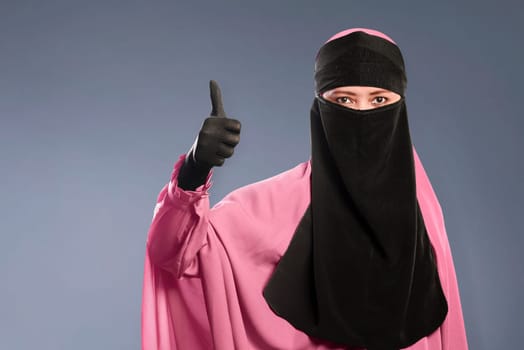 Portrait of asian muslim woman in hijab showing fine sign over dark background