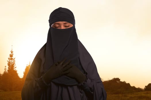 Beautiful asian muslim female in veil with niqab standing on the field