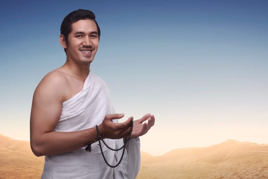 Happy asian muslim man wearing ihram clothes and prayer beads ready for hajj