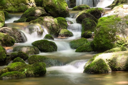 Mountain stream in the forest,waterfall with moss covered stones and long exposure