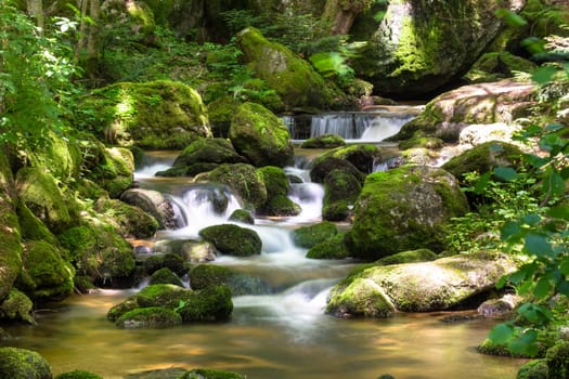 Mountain stream in the forest,waterfall with moss covered stones and long exposure