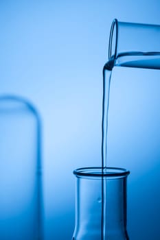 Filling an Erlmeyer flask from a reagent laser against a blue tinted studio background.