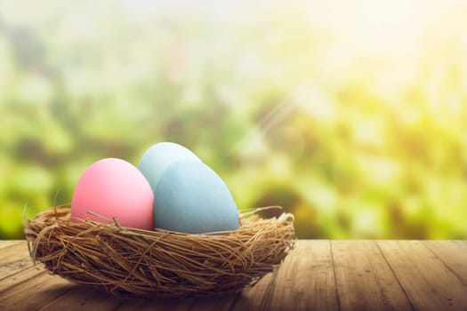 Colorful easter eggs in the nest on wooden floor over blurred background