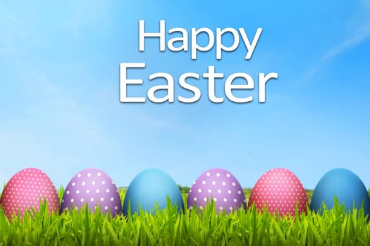 Easter eggs with happy easter greeting in the green field meadow
