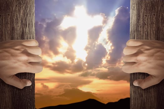 People hand open the door with cross shaped in the sky at sunset