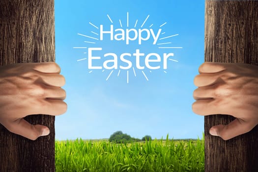 People hand opening door with happy easter greetings on meadow grass