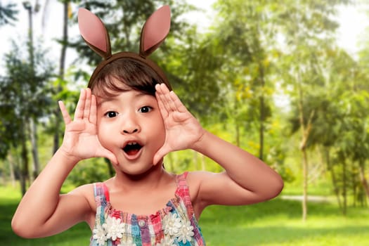 Cute little asian girl wearing bunny ears on Easter day on the field