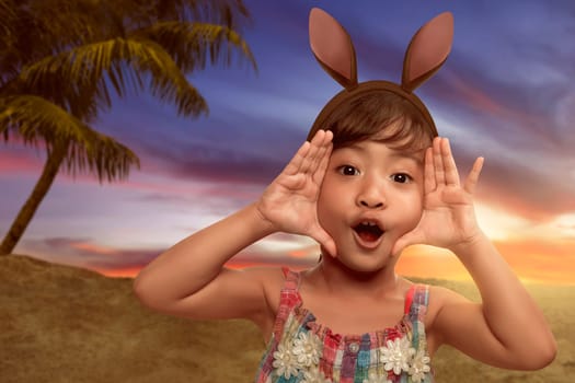 Cute little asian girl wearing bunny ears on Easter day on the beach