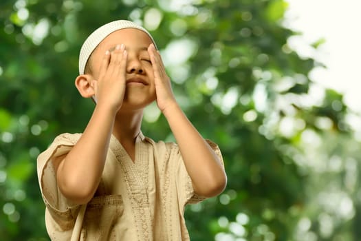 Little asian muslim child in traditional dress praying with abstract background