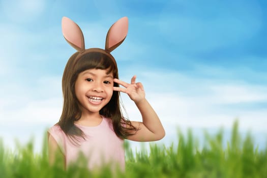Smiling girl using bunny ears in her hair on the meadow