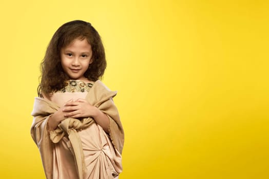 Cheerful asian muslim child with traditional dress over yellow background
