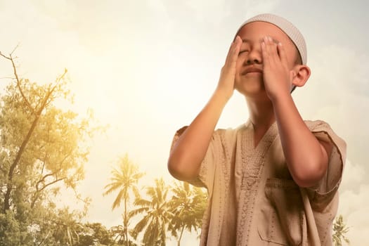 Religious asian muslim boy praying to god with sunset background