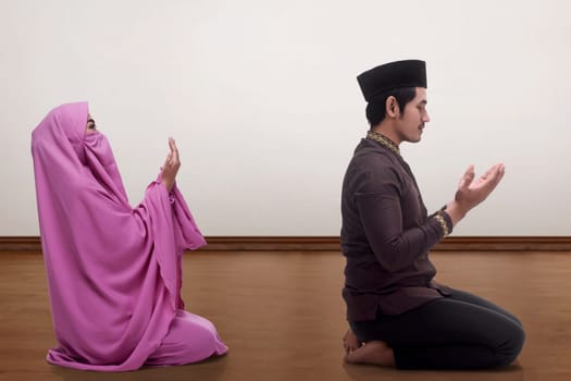 Asian muslim man and woman praying together inside the room