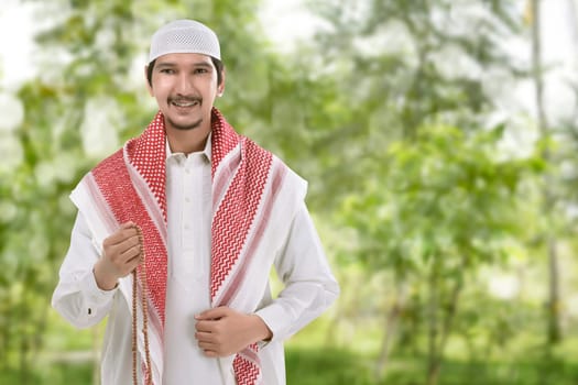 Religious asian muslim man with prayer beads standing in the park
