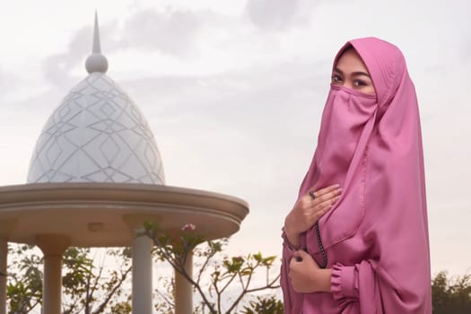 Religious asian muslim woman with traditional dress holding prayer beads in the mosque