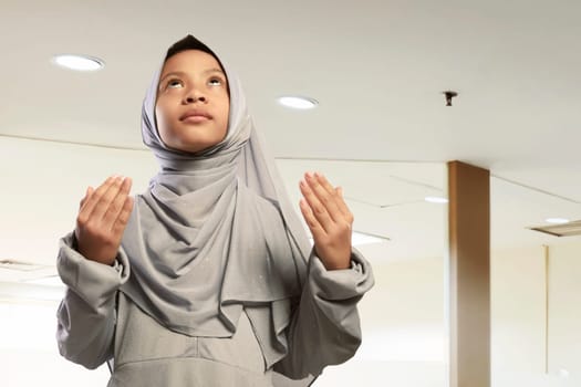 Portrait of asian muslim child wearing hijab dress praying in the mosque
