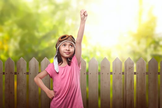Funny asian child dressed in aviator hat and goggles having fun in the park