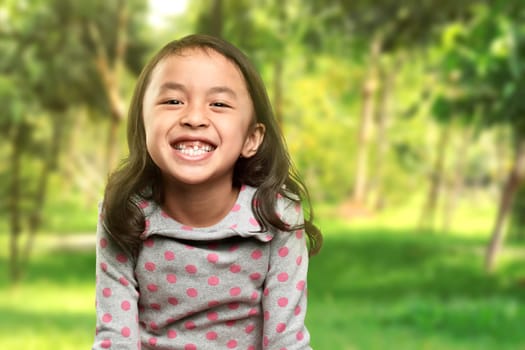 Funny asian little girl smile with her broken tooth in the park
