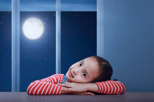 Portrait of asian child lying down on the table at night