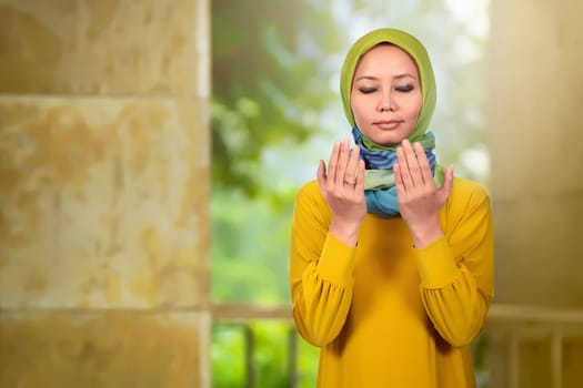 Young asian muslim woman praying in the mosque