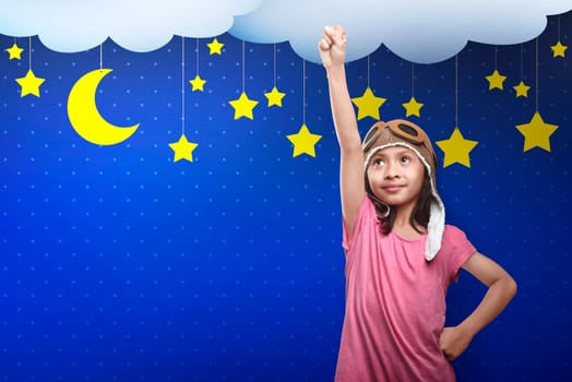 Asian child in astronaut costume dreaming of becoming a spaceman with yellow stars on blue wall background