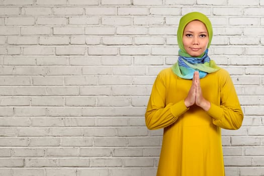Asian muslim woman praying over white wall background