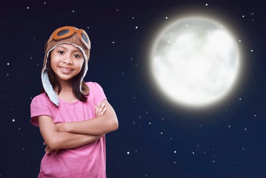 Cheerful asian child wearing aviator cap and googles standing on the moonlight at night