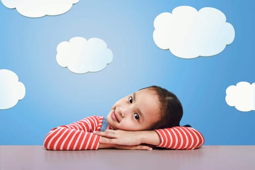 Beautiful asian little girl lying down on the desk with funny background