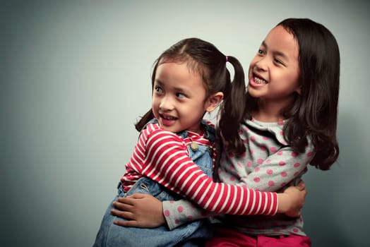 Portrait of two asian little kids with scared expression over grey background