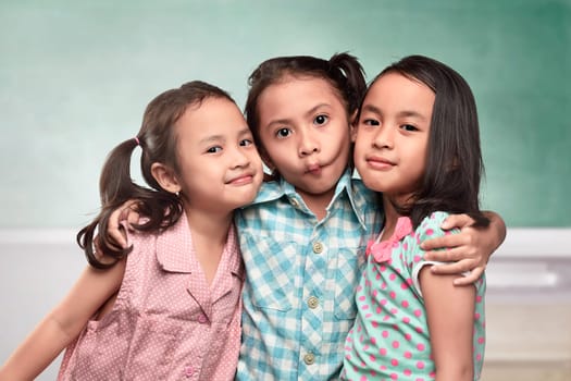 Group of asian kids with funny expression standing in front of the chalkboard