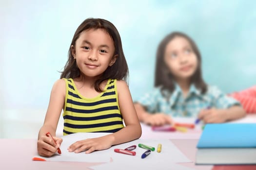 Group of asian little girl at the table and drawing with crayon in the classroom