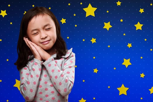 Smiling asian little girl recline to her hands under her head against funny background