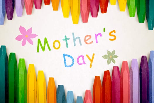 Row of colorful crayon with mothers day message over stripe pattern paper