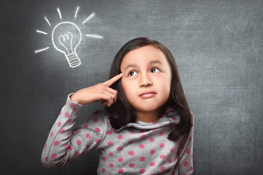 Funny asian girl thinking for new idea with white bulb in blackboard background