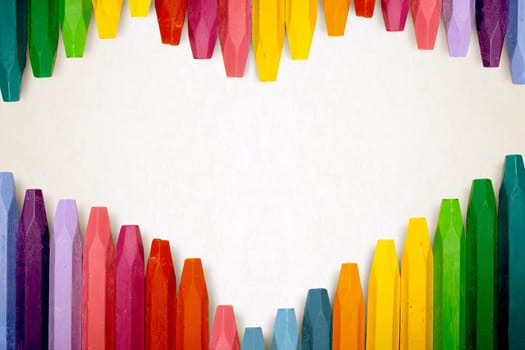 Row of colorful crayon over stripe pattern paper for copyspace