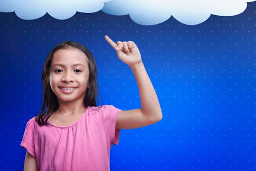 Happy asian child with a new idea in her head over blue background